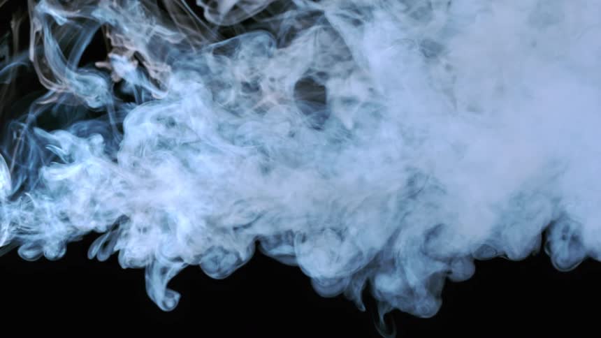 Light shines on a cloud of white smoke moving across the darkness