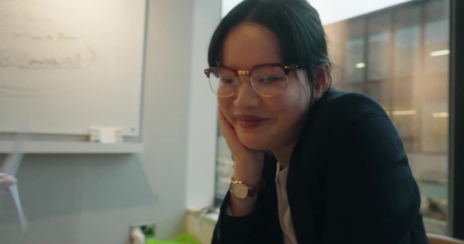 Woman in a suit looks at the laptop while resting her face on her hand