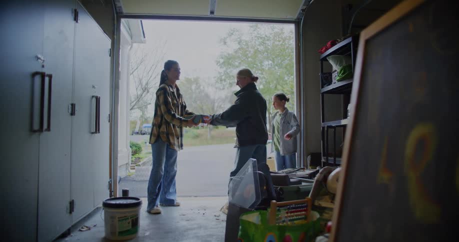 Person points while others organize items on a shelf inside the garage