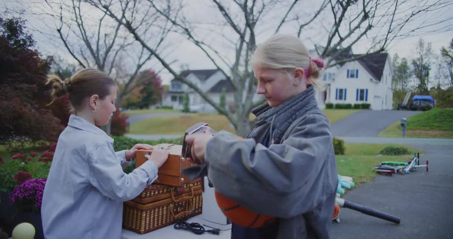 Children sort items on a table outdoors in a residential neighborhood