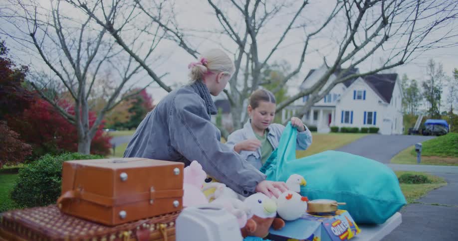 Children organize toys on a table in front of a house
