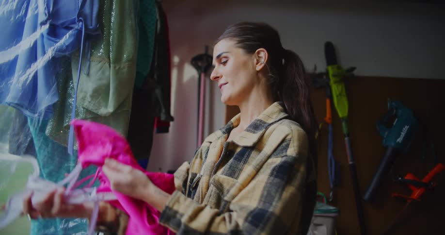 A woman picks out used apparel hanging on a rack in a garage