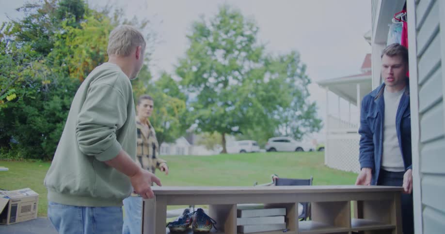 Men carry a shelf out of a garage in a residential area