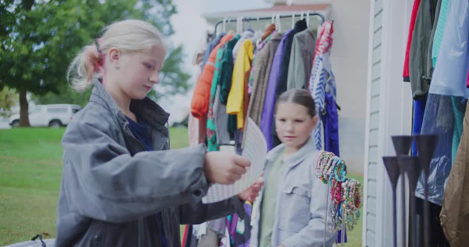 Children hold a sticker sheet and look at bracelets on display