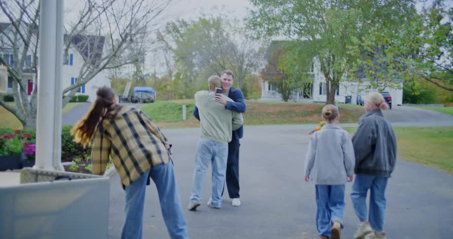 Group of people greet each other in a driveway in a residential neighborhood