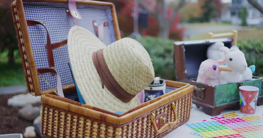 A straw hat sits inside an open wicker basket at an outdoor market
