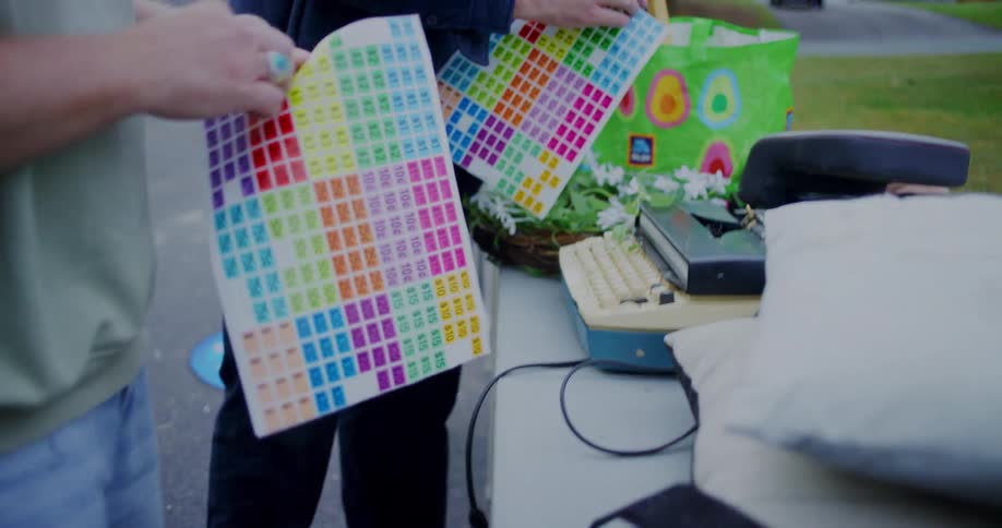 People add color coding stickers to the items they are selling at a yard sale on an autumn day