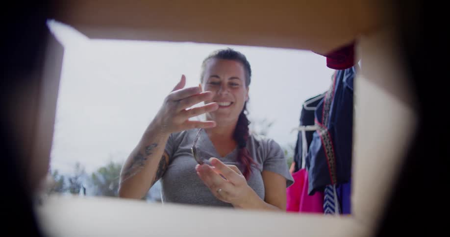 Woman reaches for an item inside a box seen from its opening