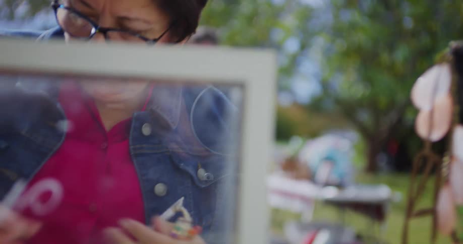 A woman picks up a colorful bracelet with a tag and places it on a table in front of her