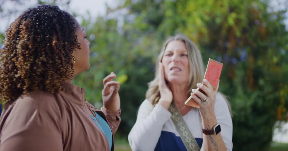 Woman holds a notebook while talking to another person outdoors