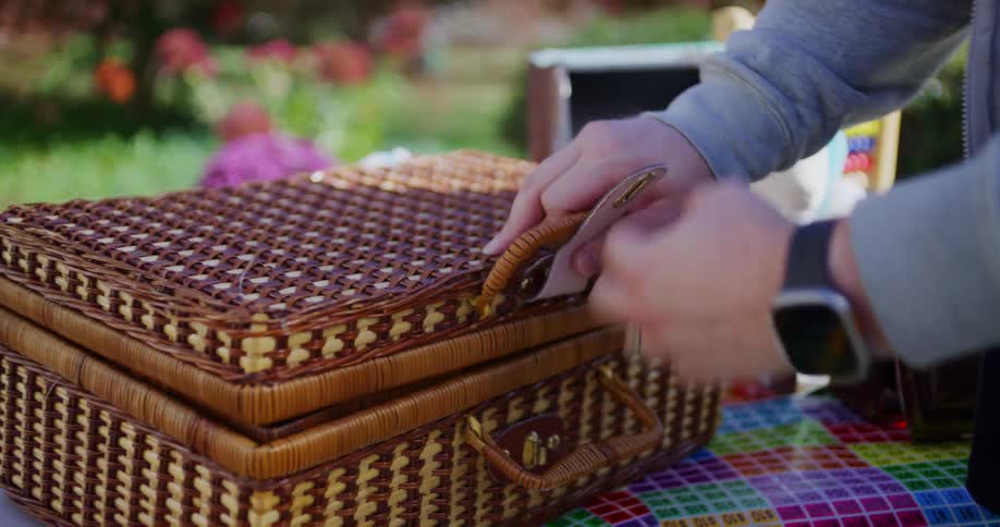Adult hand opens an empty wicker basket on an outdoor table
