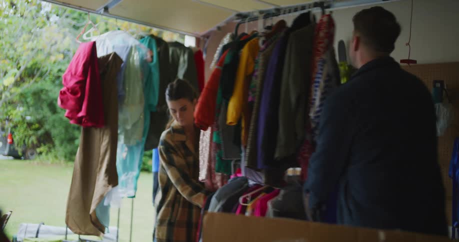 People look through clothes hanging on a rack inside the garage