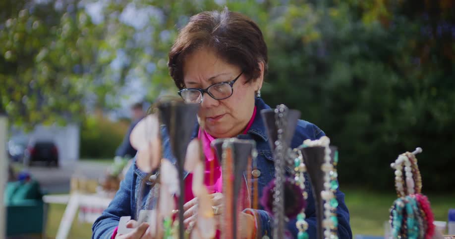 Woman looks at jewelry displayed at an outdoor stand