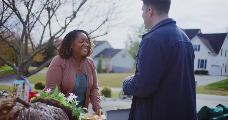 Woman hands money to a man during a purchase at a garage sale