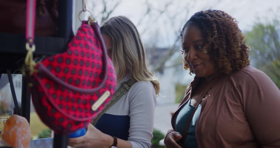 Woman holds a pair of maracas while talking to another person at an outdoor thrift sale