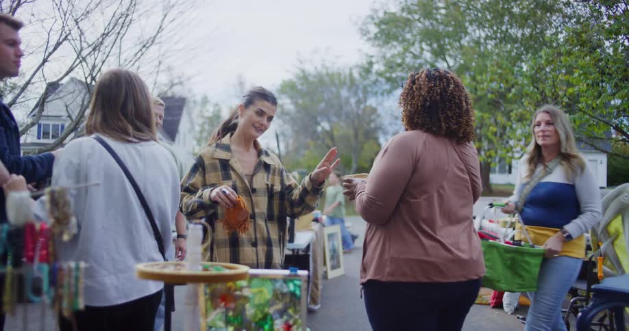Some people are standing in front of a garage sale and are talking