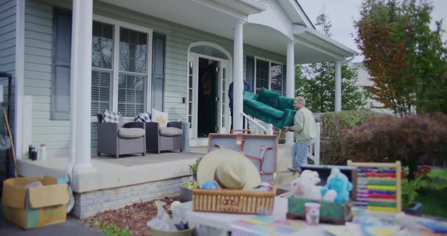 Two young men moving furniture from inside to outside a building in a suburban community during daytime