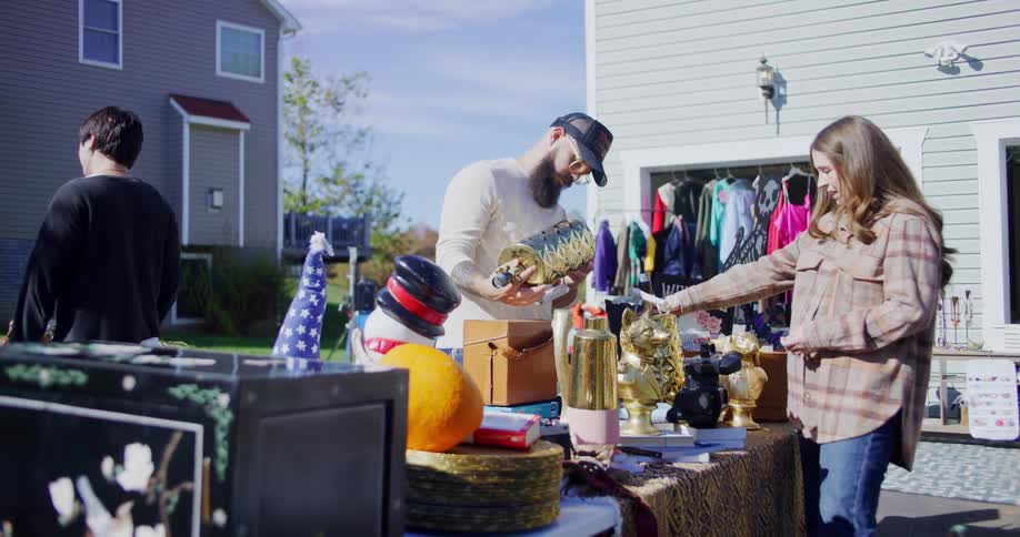 Man and woman examine golden decorative items at an outdoor garage sale