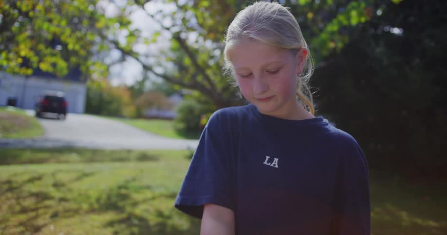 The video shows a transaction taking place outdoors likely at a yard sale or lemonade stand on a sunny day an adult hands a few dollar bills to a young girl who counts the money and places it into a metal container