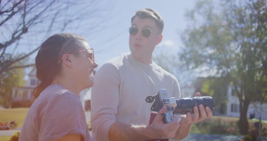 Man takes a photo with a professional camera beside another person in a residential area
