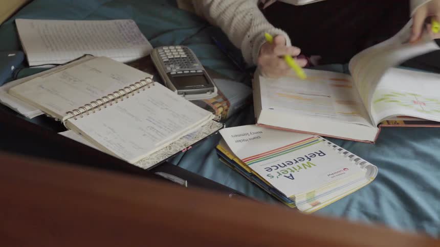 Person on bed looking through study books