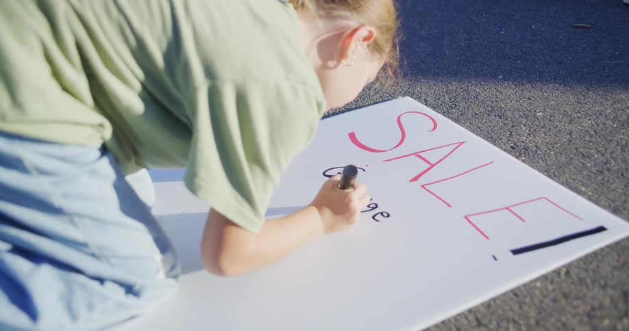 A child writing a sign for a yard sale