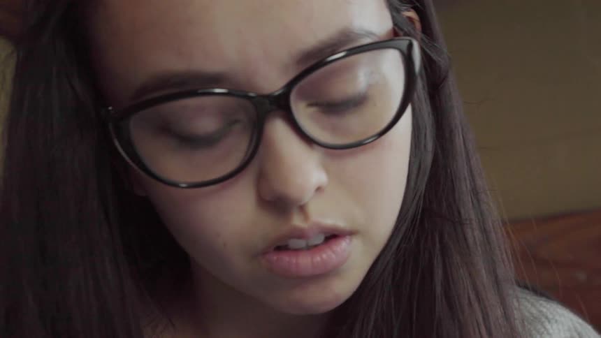 A woman wearing glasses looks down at something