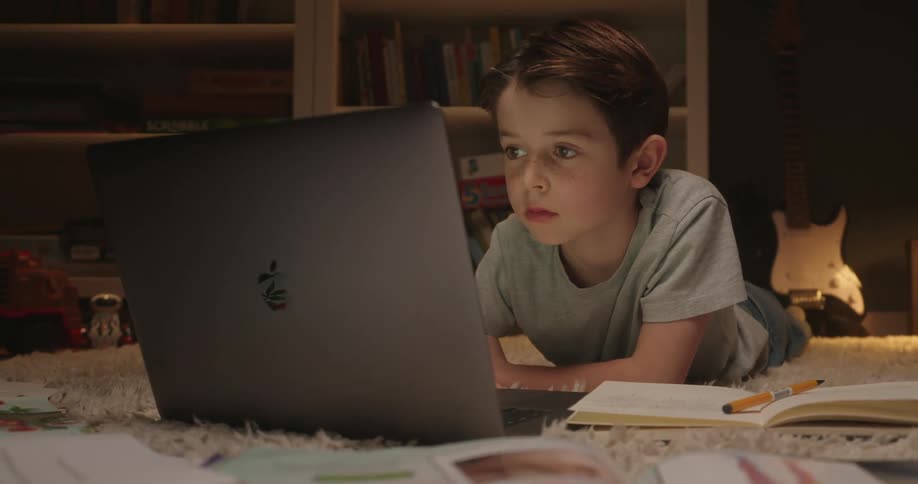 Little boy lying on the floor typing on a laptop computer