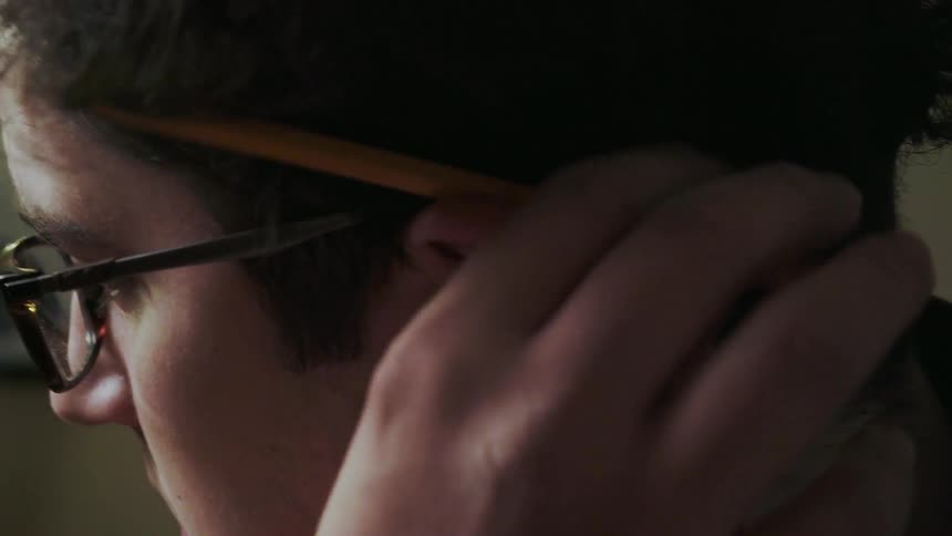 A man takes a pencil out from behind his ear
