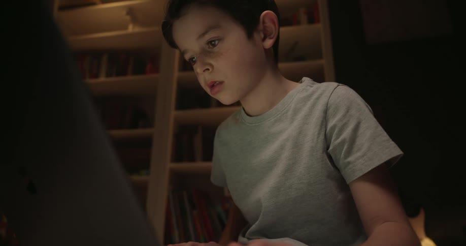 Little boy sitting at a table typing on a laptop computer