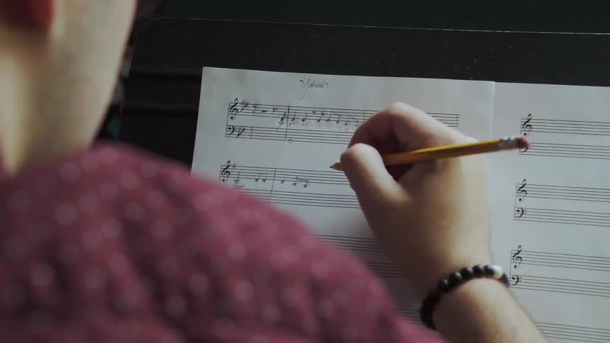 Person writes music notes on a piece of paper