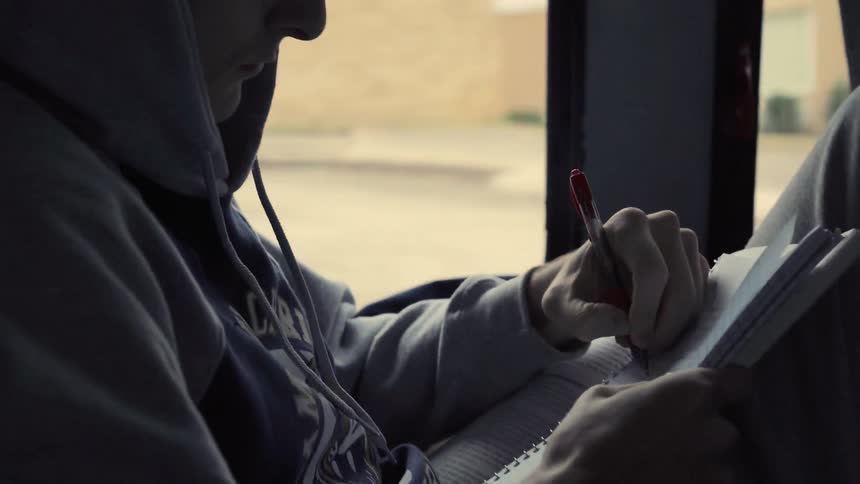 A man looks through some books and writes something