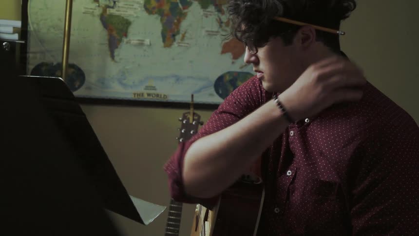 A man plays an acoustic guitar and composes music