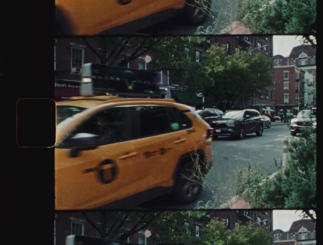 Traffic including a cab drives along a city street passing a grocery store
