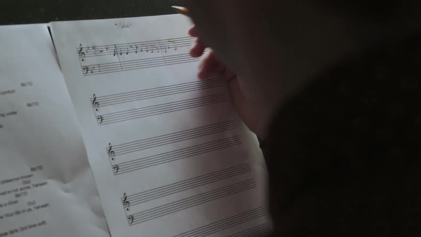 A man composes a song on blank music paper