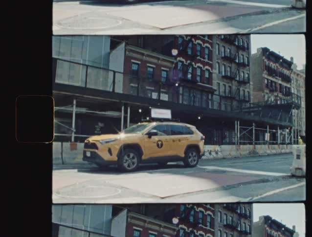 A yellow new york city taxi drives down a city street lined with brick apartment buildings and construction scaffolding filmed on 16mm film stock