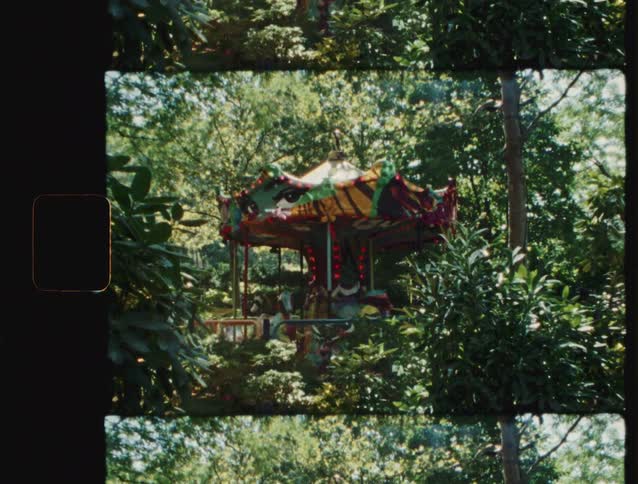 Colorful carousel appears among dense trees in a park