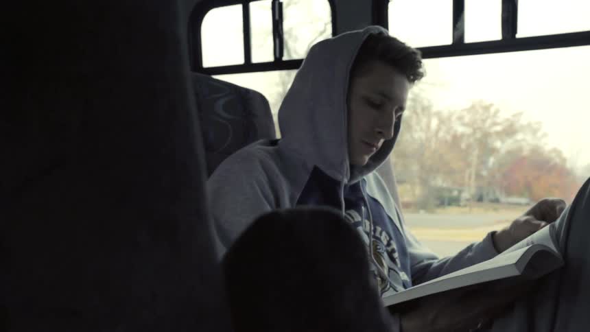 A man reads a book on a bus