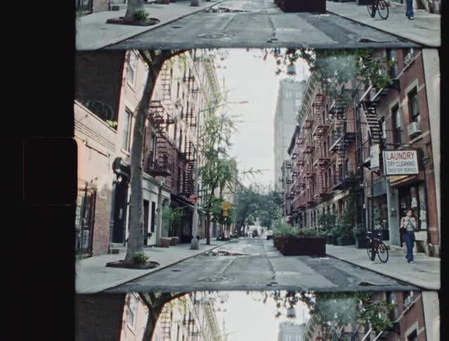 Narrow street with brick buildings trees and people walking and cycling
