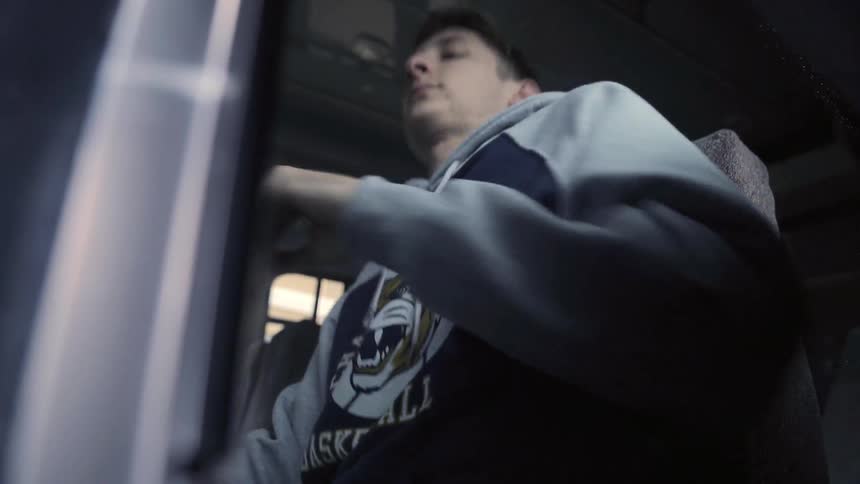 A young man sits down in a bus or subway seat
