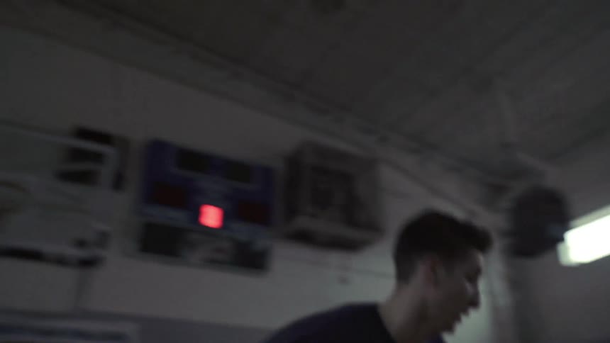 A man exercising in a gym by lunging back and forth
