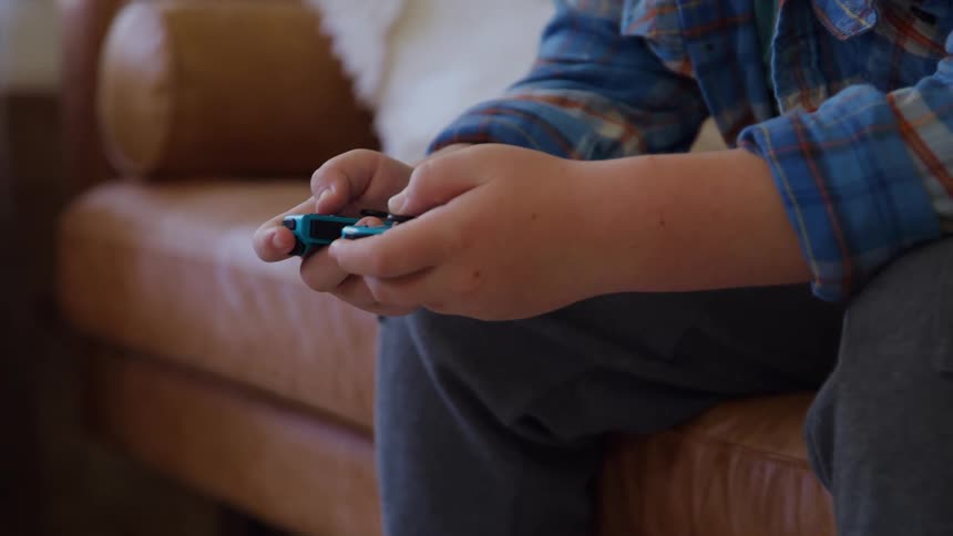 Child holds a video game controller while sitting on a couch