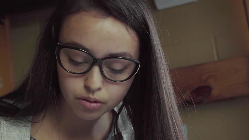 A girl in glasses sits on a bunk bed