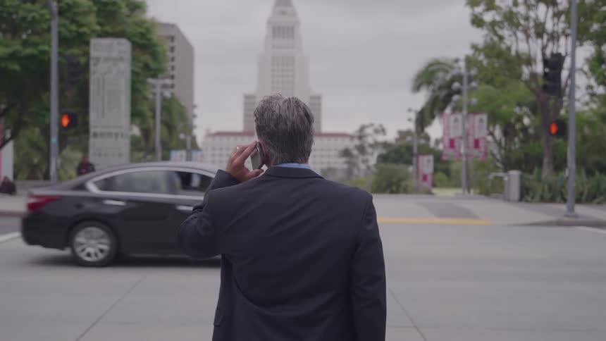 Man in a suit walking on the street talking on the phone
