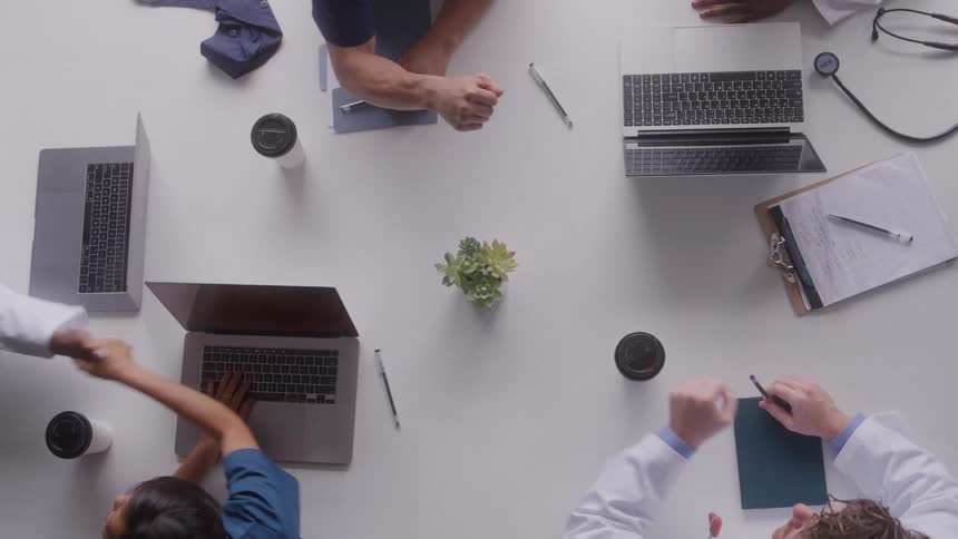 A group of healthcare personnel greeting each other while seating at a table in an office during daytime