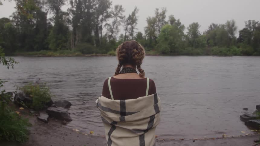 The woman is standing by the river bed