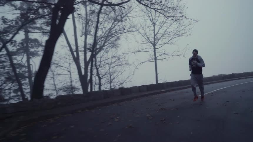A man jogs on a rural road on a foggy day