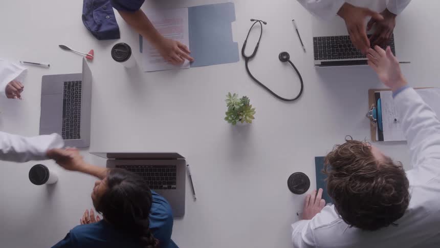 A group of coworkers shaking hands at a table