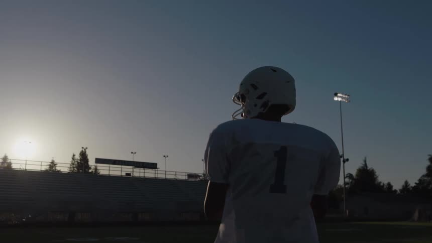 Football player holds the ball moving on the field before throwing a pass