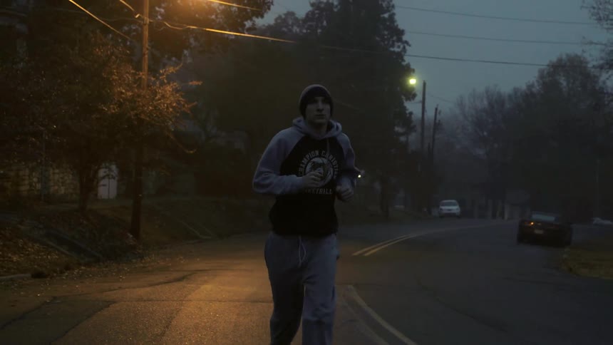 A man is jogging in the street at dawn